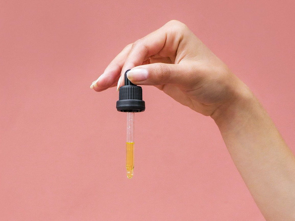Hand hält Pipette mit Lachsöl